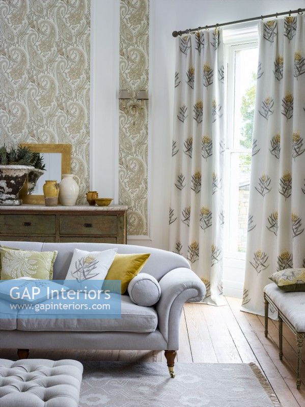 Living room with grey sofa, patterned wallpaper and curtains