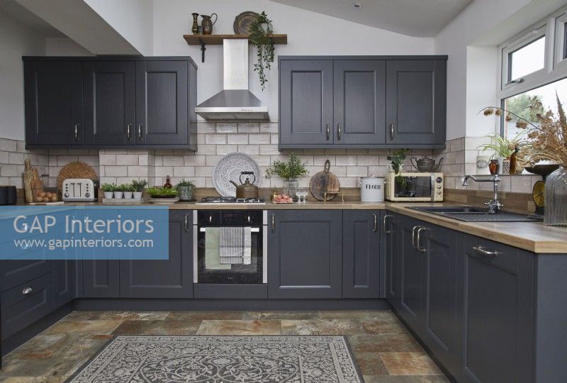 Kitchen with dark grey cabinets, slate floor tiles and vintage accessories.