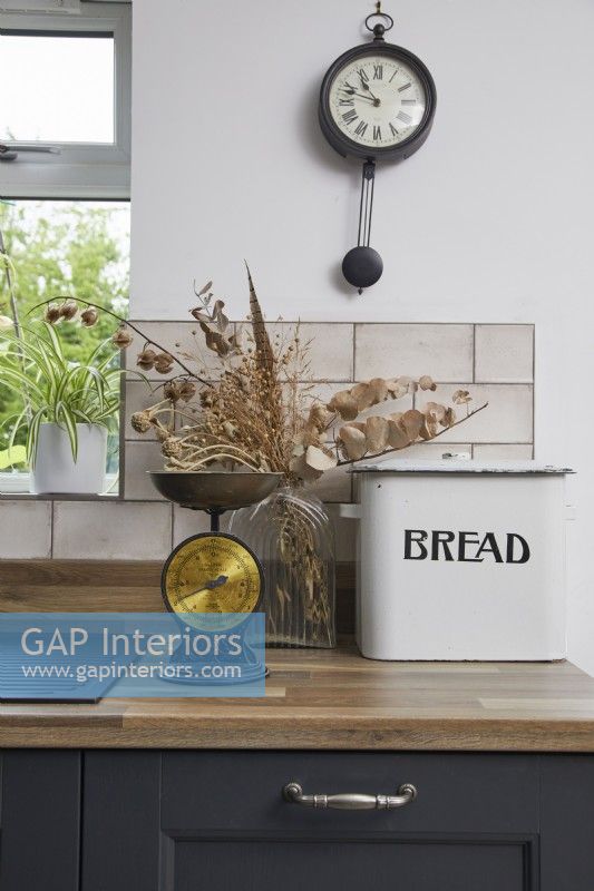 Kitchen detail showing grey cabinets, vintage scales and bread bin.