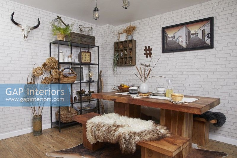 Dining area with a wooden table, industrial style shelving and white brick wallpaper.
