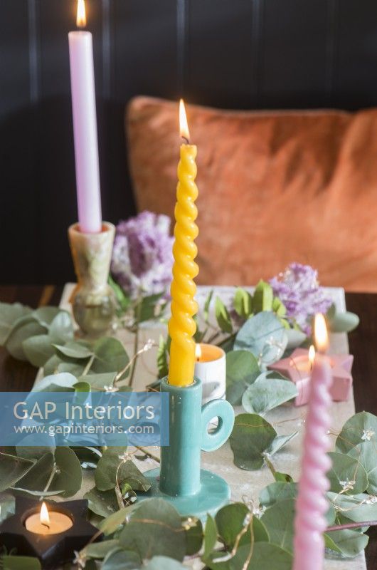 Detail of pastel coloured candles on dining table