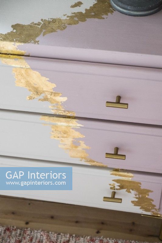 Detail of chest of drawers painted and decorated with gold leaf