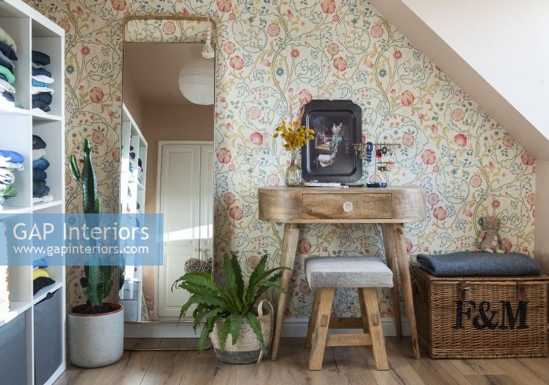Wooden dressing table against floral wallpapered wall