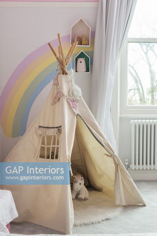 Play tepee tent in childrens room with rainbow painted on wall 