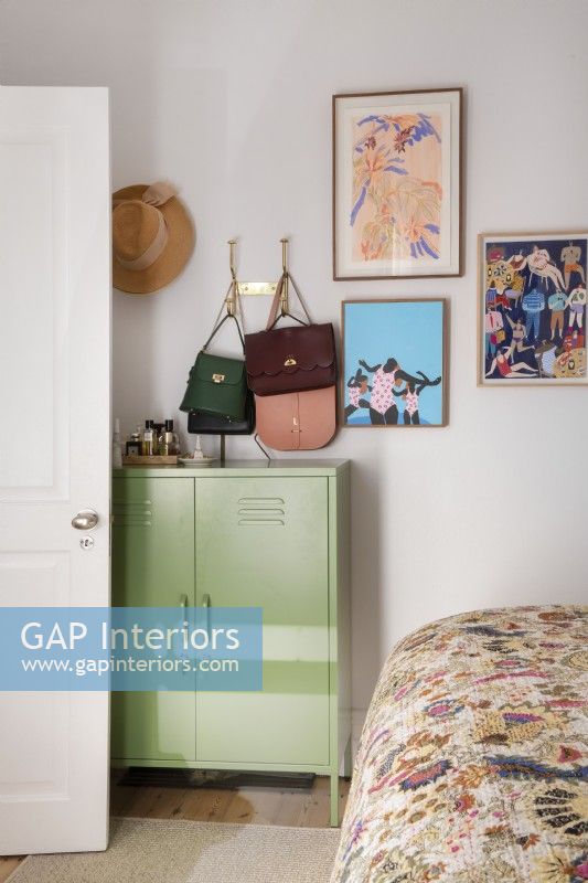Corner of bedroom with cabinet, handbags and artwork