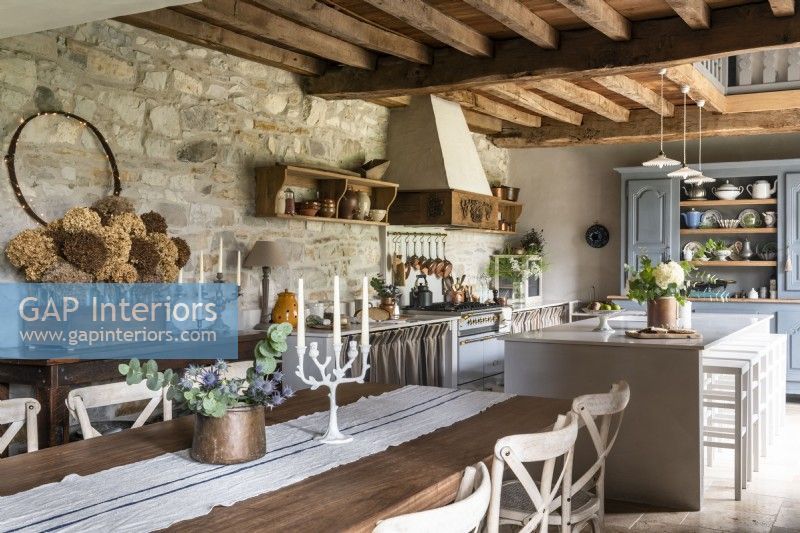 Large wooden dining table and modern white island in country kitchen