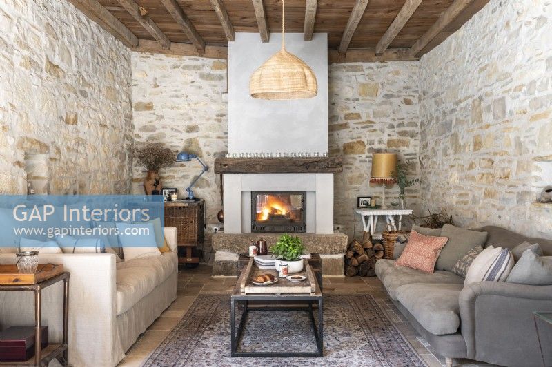 Country living room with exposed stone walls and lit fire