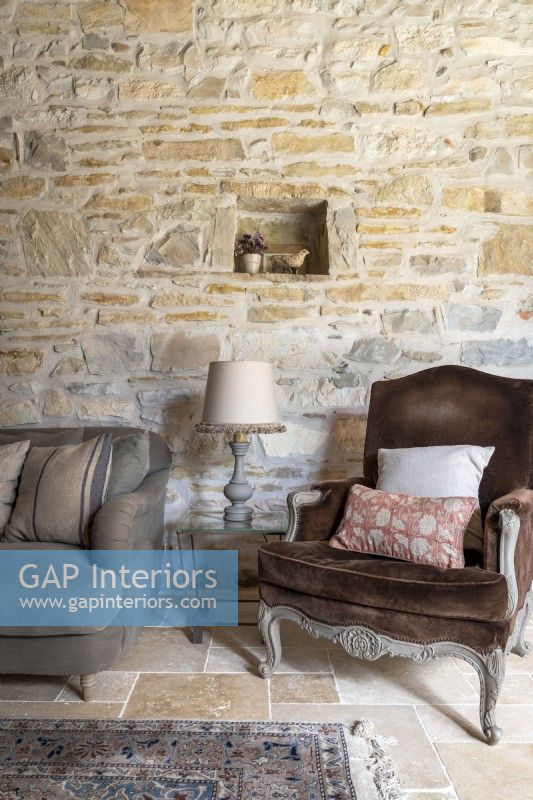 Brown velvet armchair in country living room with exposed stone walls