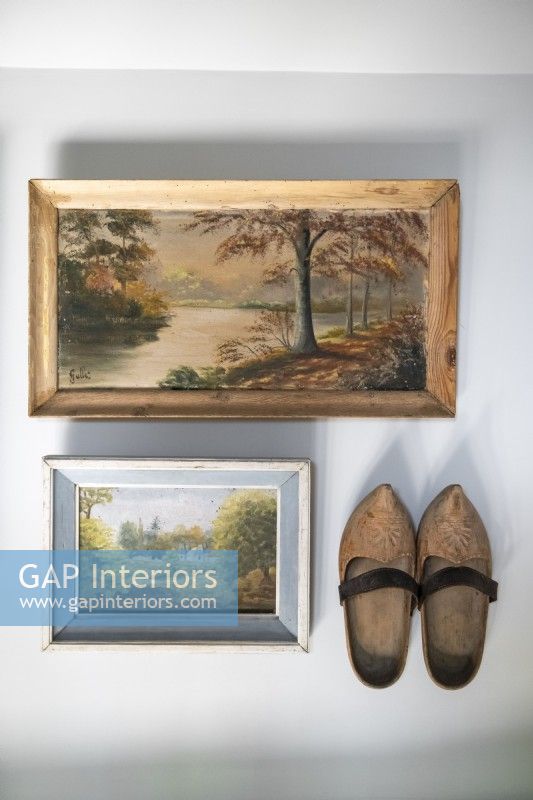 Vintage paintings and wooden shoes on wall - detail