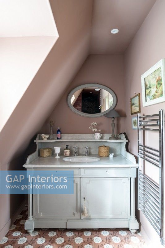 Dusky pink painted walls and vintage style vanity unit with sink 