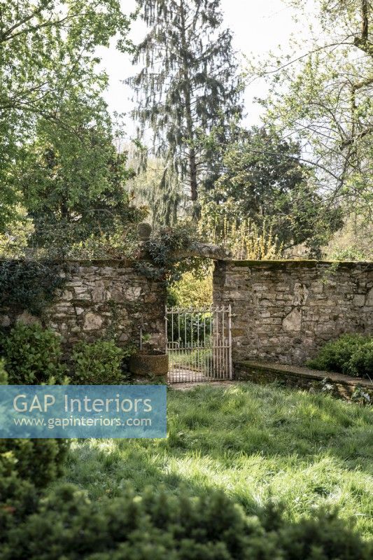 Stone wall and metal gate in country garden