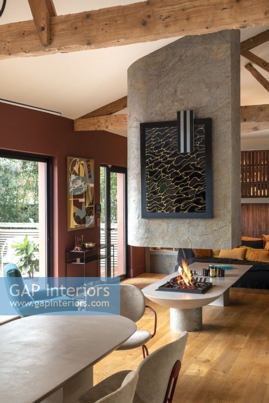 Lit fireplace in centre of contemporary open plan living space