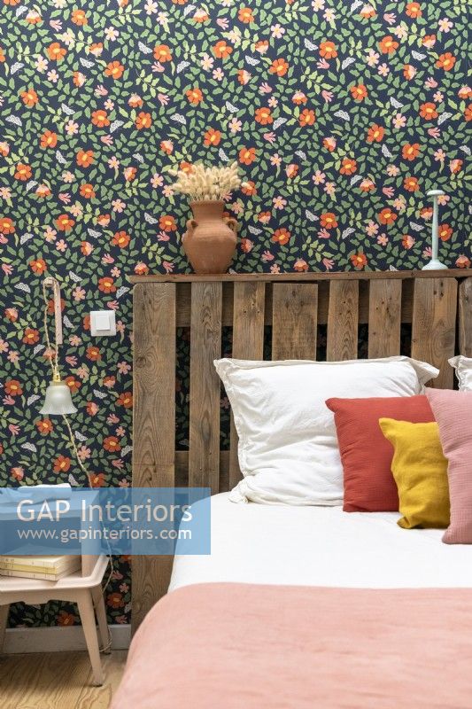 Detail of colourful wallpaper and recycled wooden pallet headboard
