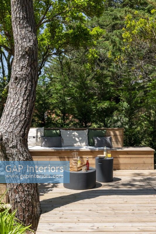 Built-in wooden bench seating with small modern tables on decking
