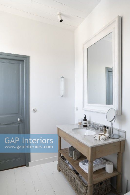 Wooden vanity unit in modern white bathroom with grey painted door