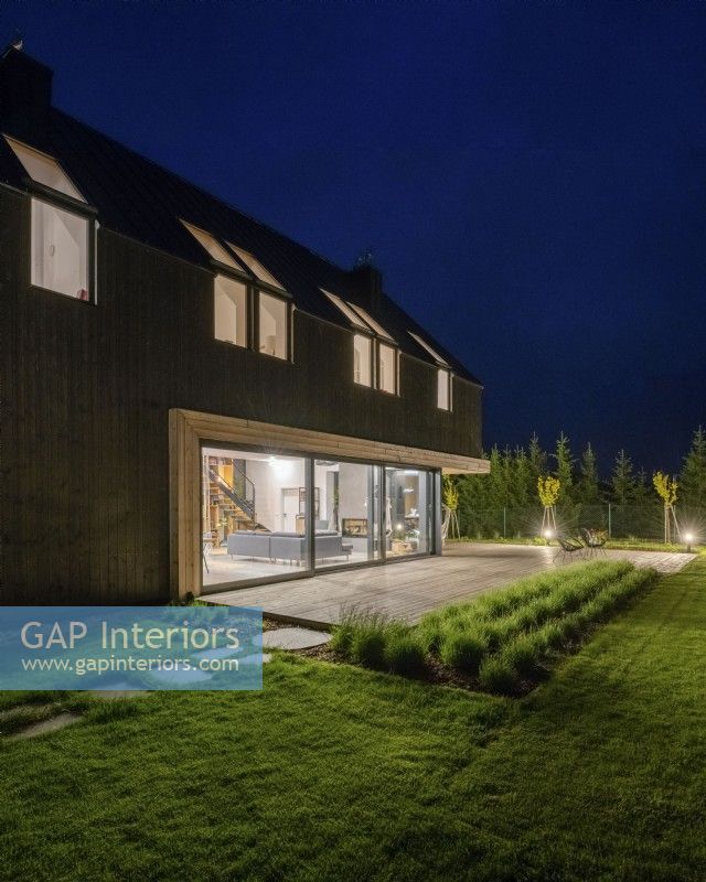 Night view from the garden to the house with illuminated interiors