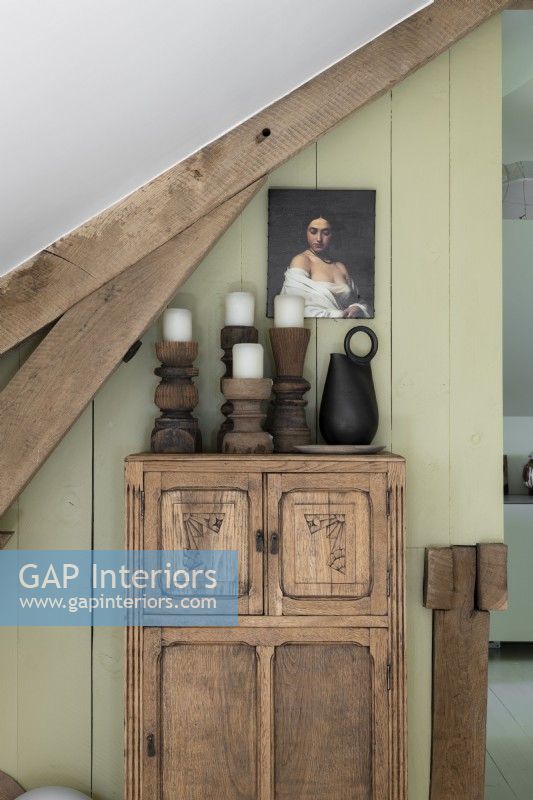 Carved wooden candlesticks on rustic cabinet with portrait painting