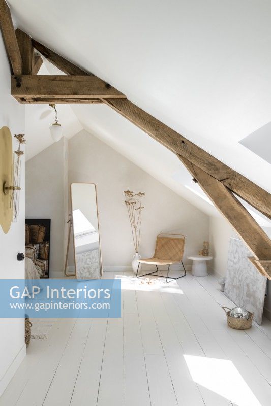 White painted bedroom in attic space with exposed wooden beams