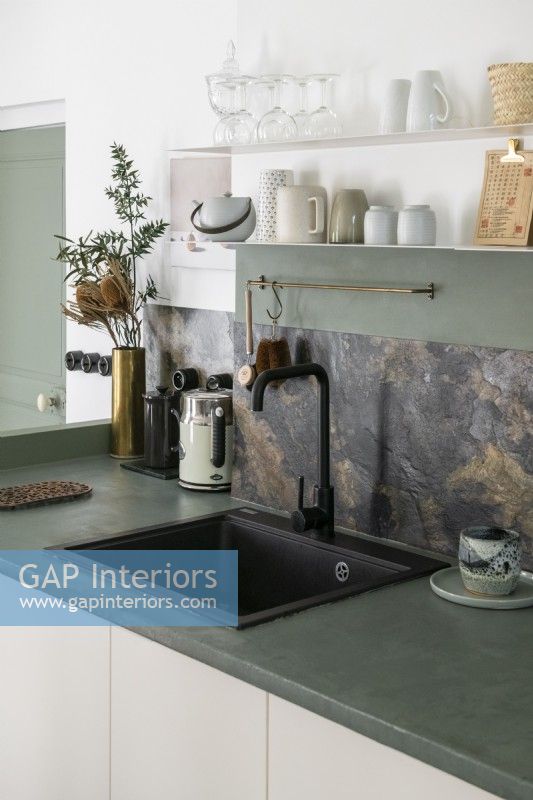 Detail of sink with marble splashback and grey concrete worktop