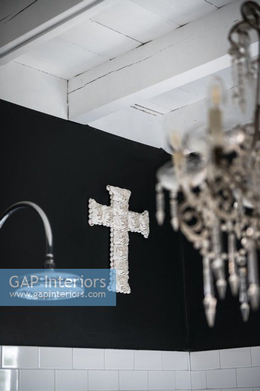 Silver cross ornament on black bathroom wall