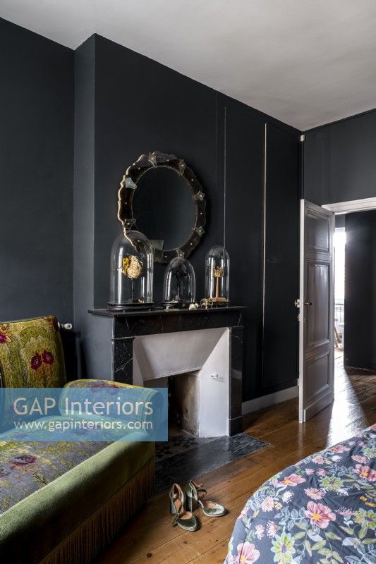 Dark grey painted bedroom with old sofa and fireplace