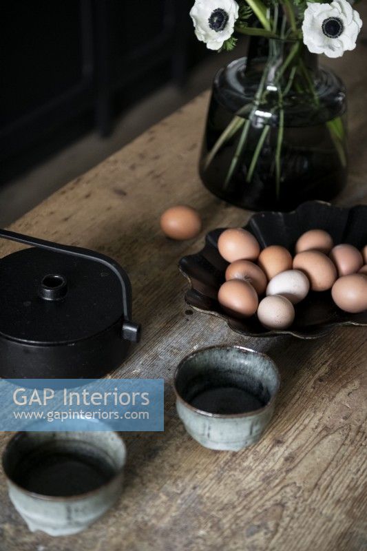 Eggs in a black bowl on wooden kitchen worktop - detail