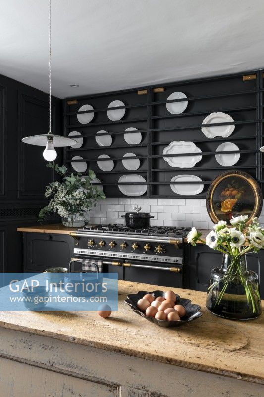 Modern country kitchen with display of white plates on black wall