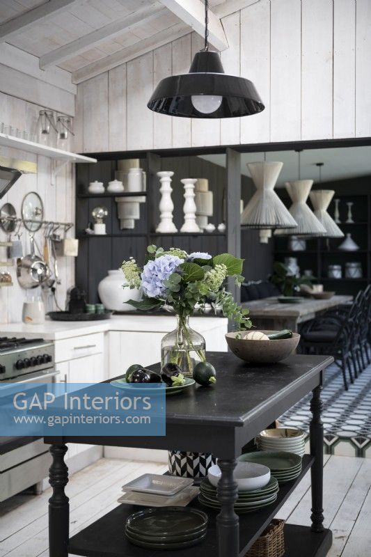 Black wooden island in country kitchen with view to dining room