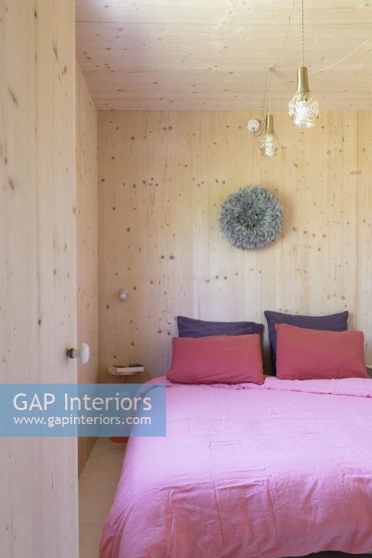 Pink bedding in wooden bedroom