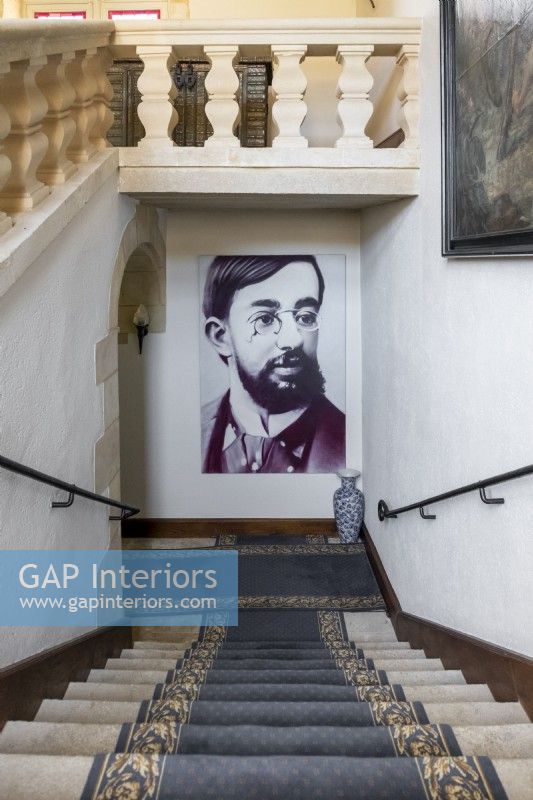 Large portrait of artist Toulouse Lautrec at bottom of classic staircase