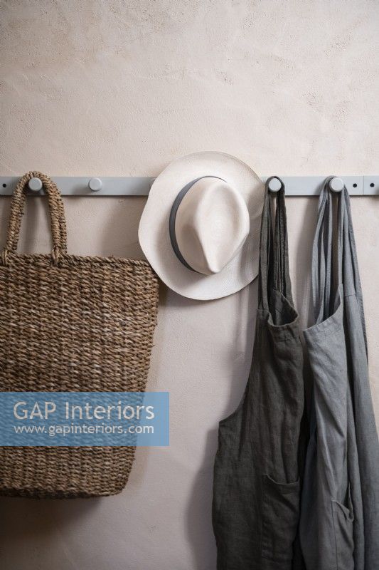 Detail of coat hooks on wall with aprons, basket and hat