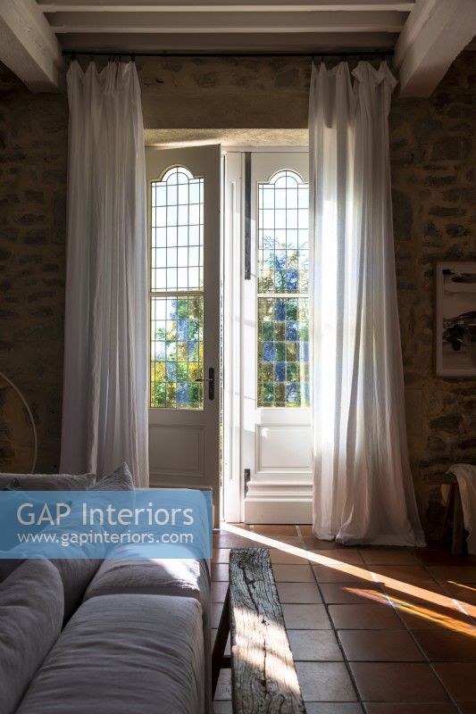 Long white drapes on French windows in country living room