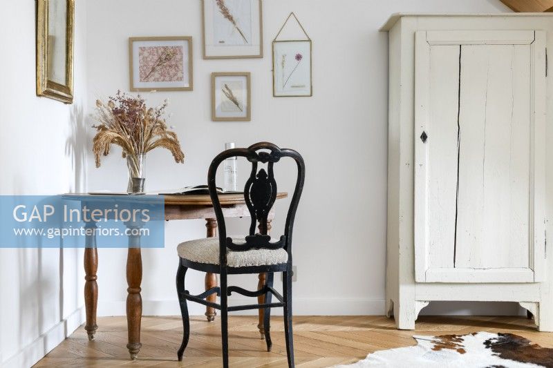 Small table and old wooden chair next to distressed wardrobe