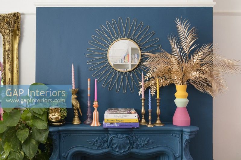 Blue painted chimney breast and mantlepiece with candlesticks and vintage mirror