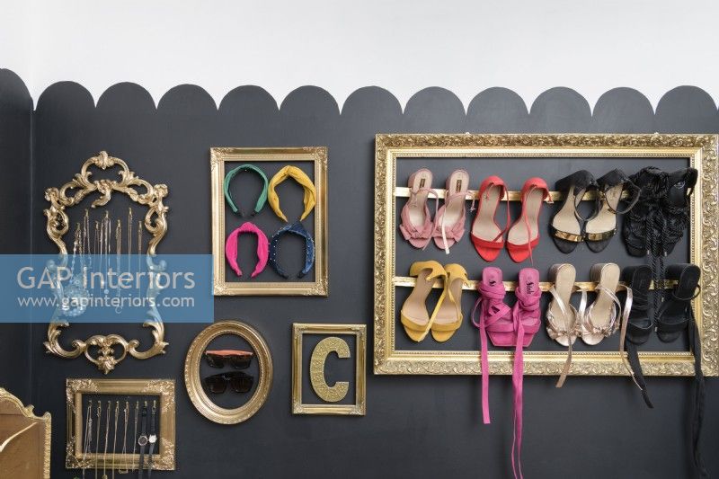Reclaimed picture frames on a black wall to display and store collections of shoes and jewellery