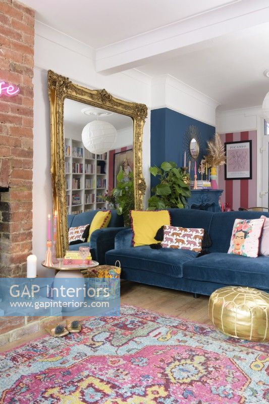 Large decorative guilt framed free standing mirror and blue sofa in a blue and pink living room