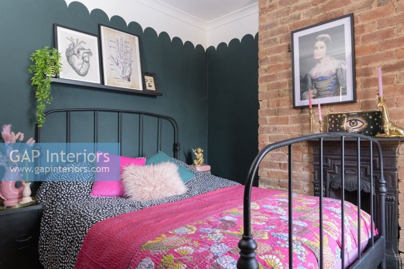 Victorian bed in a green bedroom with an exposed brick chimney breast
