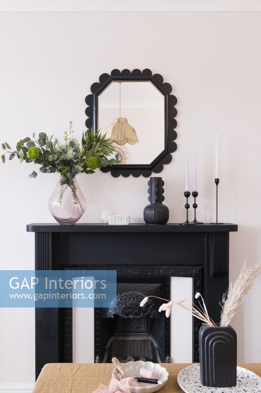 Black painted fireplace and art deco style upcycled mirror against a pale pink wall