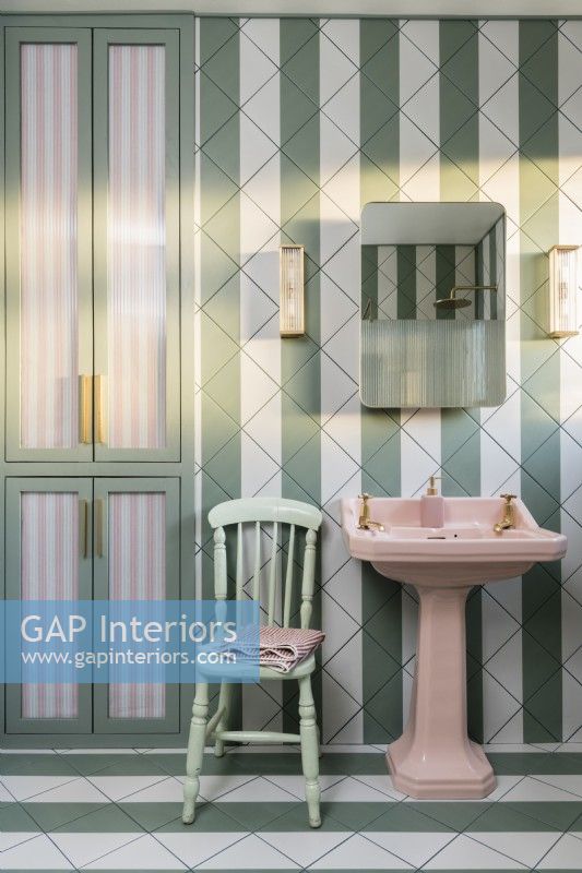 Green and white stripey tiled bathroom with pink basin
