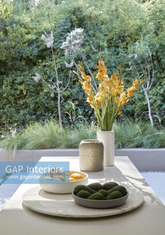 Fruit and vase of flowers on kitchen island with view to garden