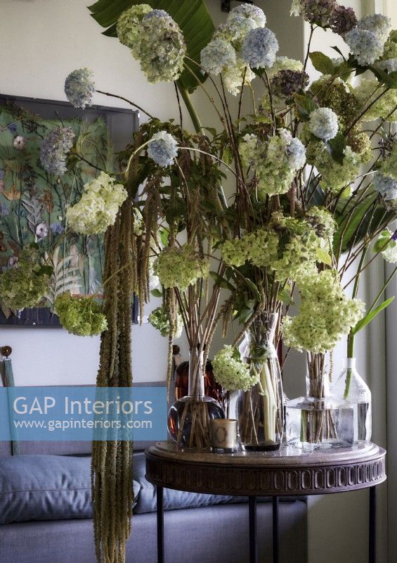 Large display of flowers in vases on small round wooden table