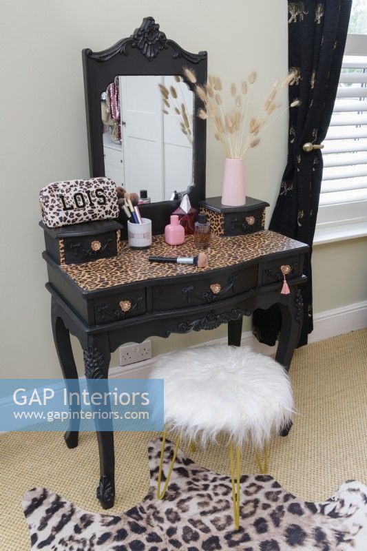 White furry covered stool and an upcycled decorative dressing table painted in black with a vinyl leopard print covered top