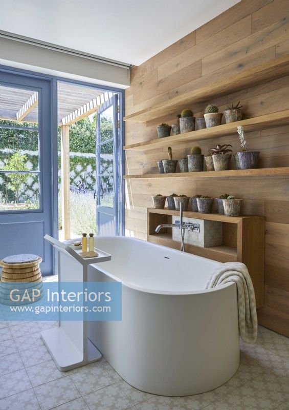 Freestanding bath in modern country bathroom with wooden walls