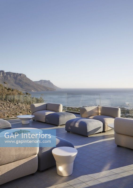 Sofas armchairs and footstools on large terrace with sea views