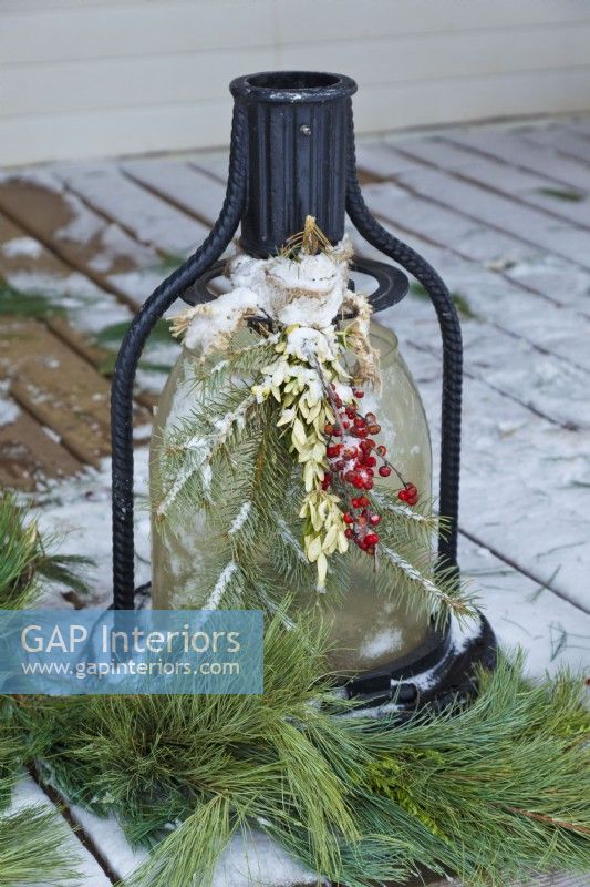 Christmas outdoor lantern decorated with greens and berries attached with burlap ribbon