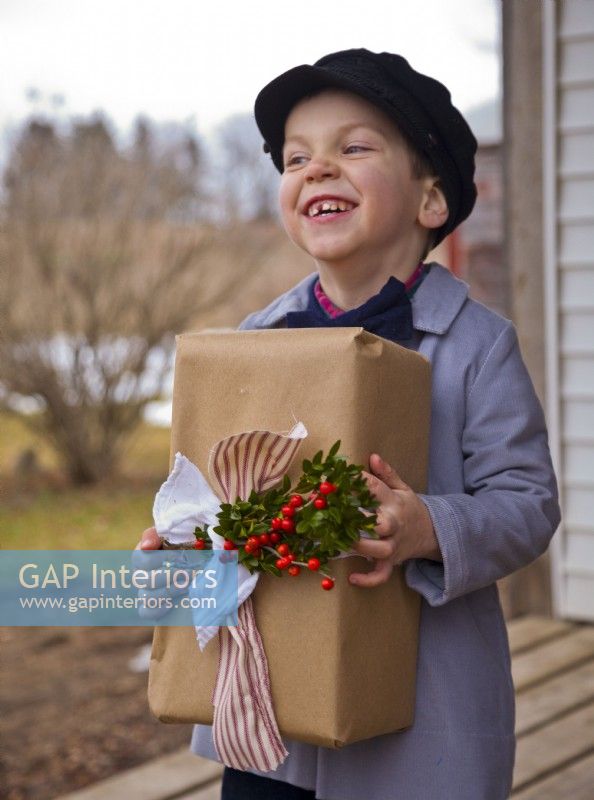 Little boy with beret holding a wrapped and decorated Christmas gift