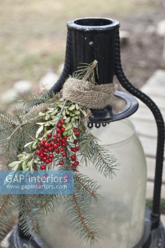 Outdoor lantern decorated for Christmas with greenery and berries