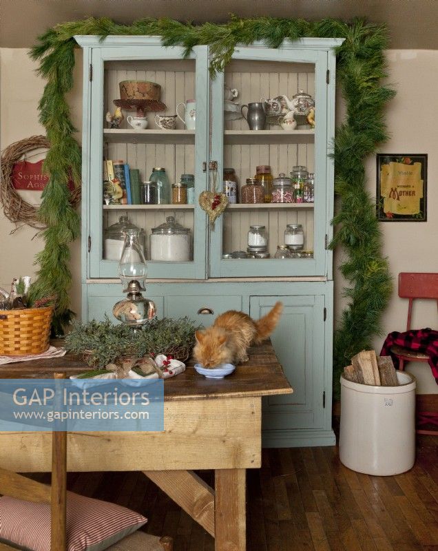 Christmas pantry and dining table with garland and wreath, and kitten on the table.