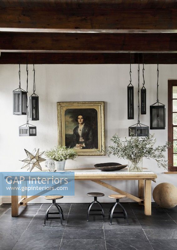 Classic portrait  and unusual pendant lights above large wooden table