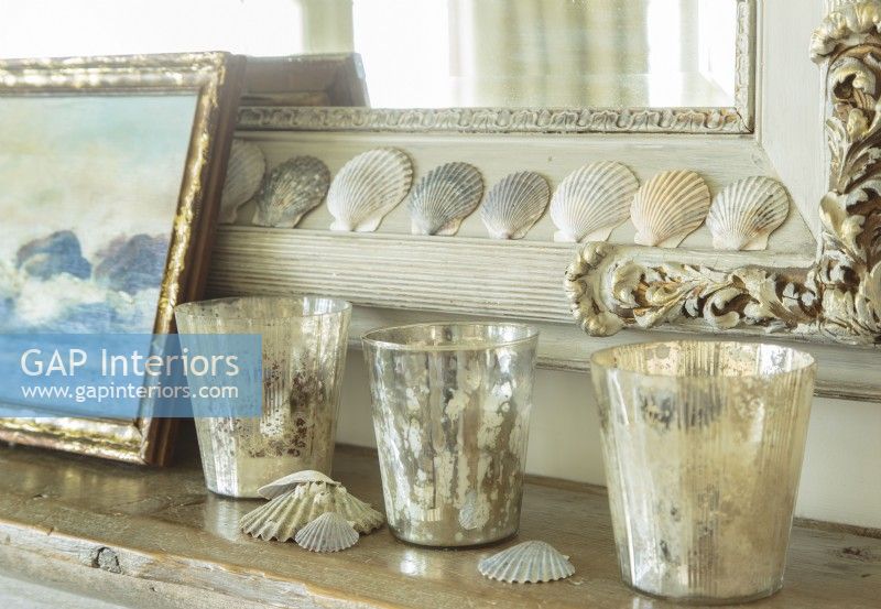 Sea shells, votives and a coastal painting pay tribute to the cottage oceanic location.